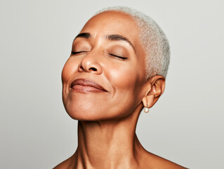 Serene portrait of an older African American woman with short gray hair, smiling with eyes closed, embracing peace and aging gracefully