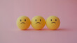 © Ice Cream Paradise - emotional, mood, sadness concept: three yellow balls with sad faces arranged in a slightly slumped pattern against an isolated soft pink background