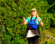 © Michael Connor Photo - two thumbs up: happy smiling sea kayak paddler on shore with hat sunglasses pfd and spray skirt trees in background room for text