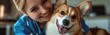© gen_pick - Smiling vet playing with Corgi dog in a veterinary clinic