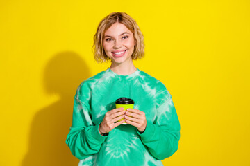 Canvas Print - Photo of charming positive woman wear green sweatshirt drinking coffee empty space isolated yellow color background