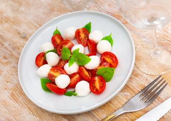 Ready-made dish of Italian cuisine is caprese salad made from slices of mozzarella cheese, slices of ripe tomatoes and basil leaves. Simple and hearty snack, independent dish