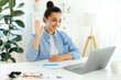 © Kateryna - Positive beautiful caucasian young woman, company seo, sits at the work desk with laptop, greeting with her hand, conducts online meeting with colleagues or client, talking via video conference, smile