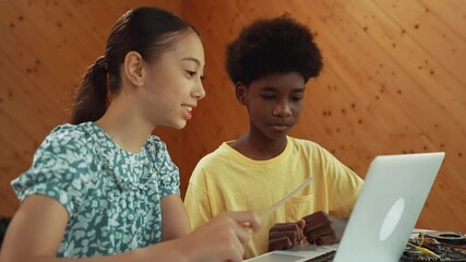 Wall Mural - Site view of african boy and caucasian girl in casual cloth working together to coding prompt or programming system at table with laptop and electronic equipment at STEM technology class. Edification