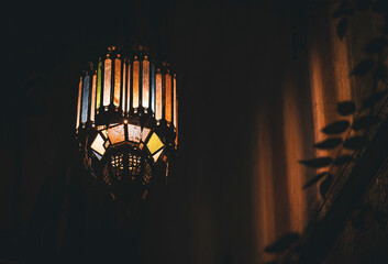 Traditional colored glass Moroccan Pendant Light Casting Intricate Shadows on the ceiling, warm inviting romantic atmosphere in a riad accomodation, medina Marrakech, Morocco