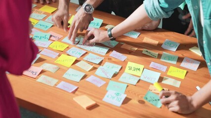 Top view of project manager sticking sticky notes and explain idea about web design. Professional marketing team or programmer brainstorming idea while looking at tablet with color palette. Symposium.