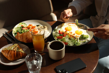 Poster - Man having tasty breakfast at wooden table in cafe, closeup