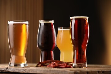 Wall Mural - Glasses with different types of beer and snacks on wooden table against color background