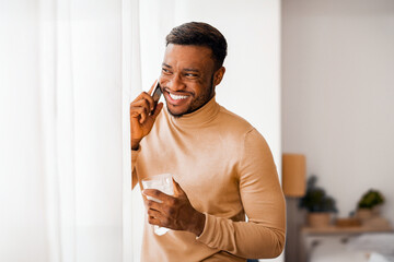Aufkleber - Phone Call. Joyful Afro Guy Talking On Cellphone Having Coffee Standing Next To Window At Home. Copy Space