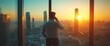 © Dayone - A businessman on a phone call, gazing at a sunset over a city skyline.