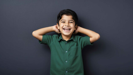 Poster - Laughing Middle Eastern boy in green shirt on plain dark navy background with copy space