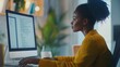 © paper later - A Black Woman in a Yellow Blouse Uses a Desktop Computer