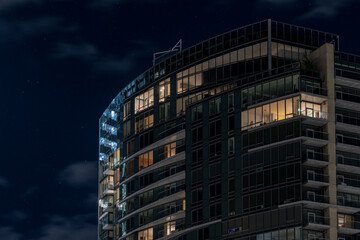 A skyscraper condo building set against a partially cloudy night sky with stars. 