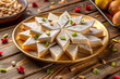 © Arethaawykoff - Delicious kaju katli arranged beautifully in star shape, garnished with colorful nuts and served on golden plate, perfect for festive celebrations