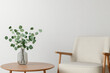 © Rutchaneewan - Serene living space, elegant chair beside a minimalist wooden table featuring a fresh green plant in a clear vase against a soft white background