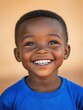 © NILSEN Studio - A joyful young child with a radiant smile and sparkling eyes, wearing a blue shirt, radiates pure happiness against a warm, blurred background.