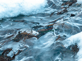 Winter landscape: a frozen stream covered with ice and snow creates an atmosphere of calm and beauty of the cold season