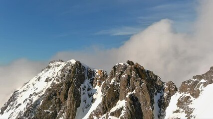 Wall Mural - Aerial view of majestic snowy mountain peaks with clouds at the summit. British Columbia, Canada.