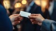 © Pornnapa - A close-up of a business professional handing over a business card, with a blurred background of a networking scene
