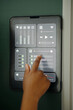© DragonImages - Close-up of hand operating digital interface of smart home control panel Adjusting various settings such as volume, light brightness, and connectivity functions