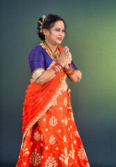 Portrait of a traditional Indian woman in a greeting pose to Namaste hands. Indian woman in traditional saree.