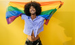 © VISTA by Westend61 - Happy gay man posing with LGBTQIA flag near yellow wall