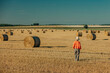© VISTA by Westend61 - Woman in orange sweater walking on agricultural field