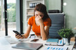 © NINENII - Young sad businesswoman is sitting at table, covering his face with his hand and talking on cell phone. On desk is laptop, tablet computer, Stress.