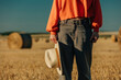 © VISTA by Westend61 - Woman in orange sweater holding hat and standing on field