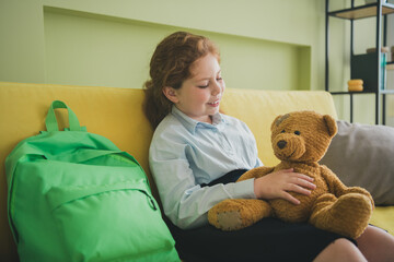 Wall Mural - Photo of cheerful cute adorable small girl sitting sofa hold her best friend soft toy teddy bear room apartment indoors