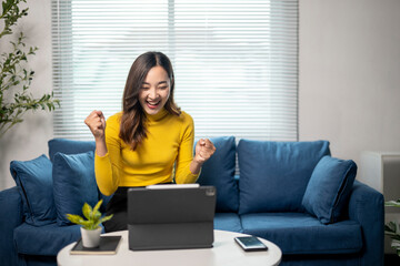 Wall Mural - young businesswoman celebrating success while working at home using tablet