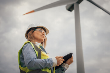 Poster - A dedicated female engineer is actively engaged in monitoring the operations of wind turbines, utilizing her expertise to ensure efficiency and sustainability in renewable energy production