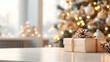 © Rabil - A beautiful gift box sits on a white table, with a blurred Christmas tree and sparkling lights in the background. There's plenty of space for adding text.