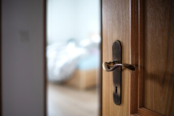 Open, wooden apartment door and vintage metal lock and handle. Close up shot, shallow depth of field, natural light, no people