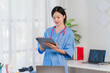 © Kritdanai - Focused Physician: A female doctor meticulously reviewing patient data on her tablet, showcasing dedication and professionalism in a modern medical setting.