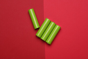 Green AA batteries on a red background