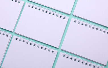 Wall Mural - Pattern of white blank spiral notepads on a mint green background