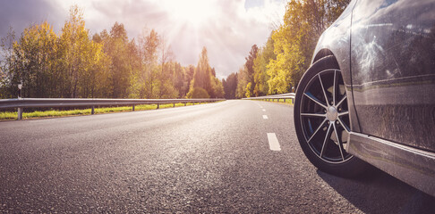 Panoramic background of the car on the asphalt road in autumnal park.