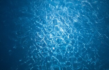 Poster - A close-up view of rippling blue water reflecting sunlight, the surface adorned with intricate patterns.