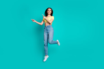 Wall Mural - Full size photo of pretty young woman jump direct fingers empty space wear top isolated on teal color background