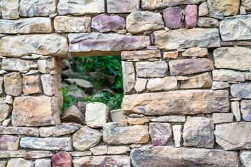 A stone wall with a small window in it