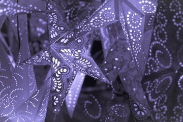 Colorful purple xmas lantern stars at christmas market season. Beautiful shiny star mood lamp in merry advent decoration. Traditional symbol of the best miracle time of the year. Part of series