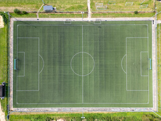 A stunning aerial shot shows a pristine soccer field with clear markings surrounded by lush greenery