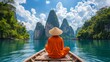 Man in orange robe on a boat in clear waters, facing towering karst mountains and dense forests under a blue sky.