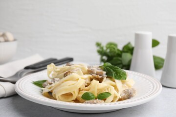 Delicious pasta with mushrooms and basil on light table, closeup