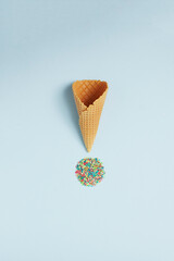 Ice cream cone and colorful sprinklers on blue background. Flat lay