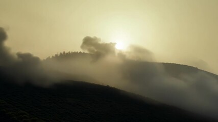 Poster - Smoke billows from a hillside at sunrise, creating an eerie scene with the sun shining brightly