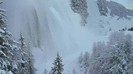 Aufkleber - Massive avalanche cascades down a snowy mountainside, blanketing the forest in a thick cloud of snow, showcasing the raw power and beauty of nature in winter