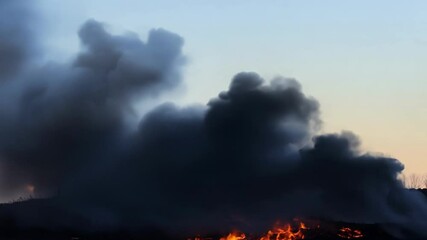 Poster - Massive fire rages, sending dark smoke into the twilight sky, posing a dangerous threat and causing destruction. The intense scene shows the raw power of nature