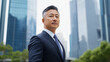 © Maksym - A distinguished middle-aged Asian man in a tailored suit stands outdoors, his calm expression and salt-and-pepper hair reflecting wisdom and experience, with the blurry modern skys